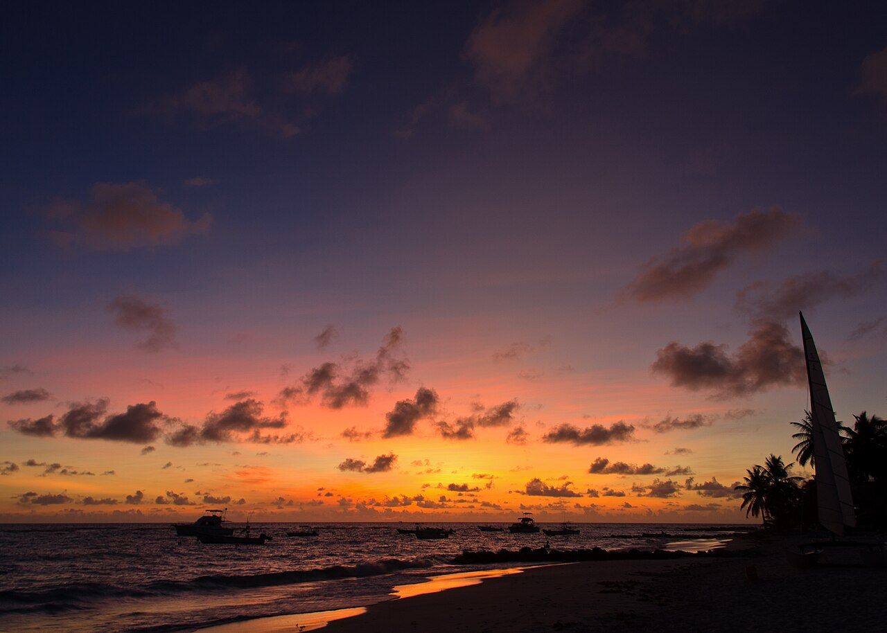 The beach at sunset in Christ Church, Barbados on the South Coast in the West Indies, Caribbean with silhoutte of boats 