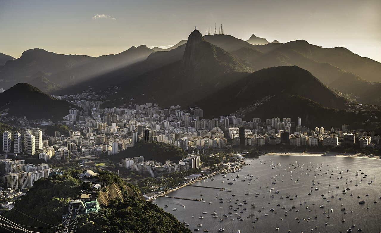 The skyline of the city and the Sugarloaf at sunset, crepuscular rays spreading over the bay. Rio de Janeiro, Brazil.