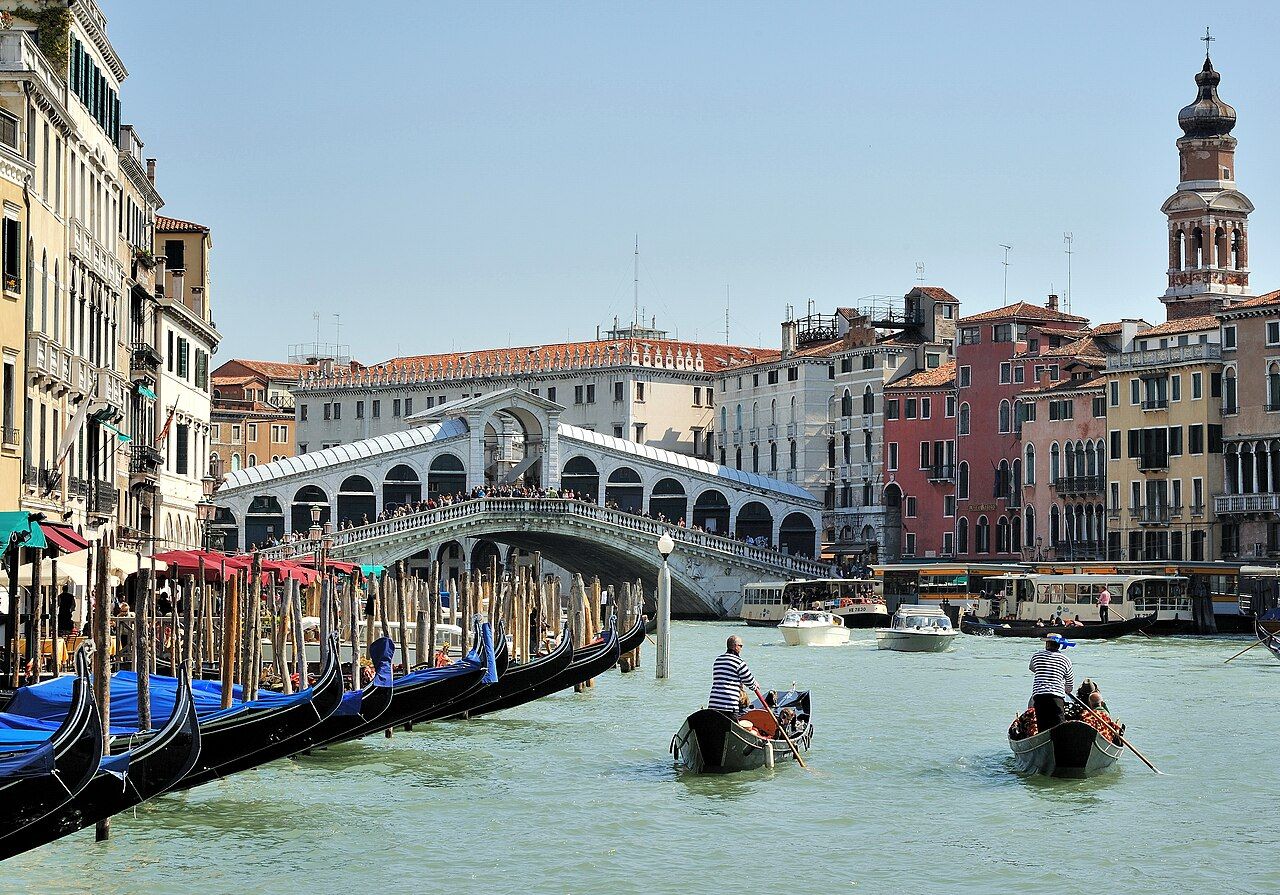 Two "sandolisti" (sandal is a typical boat in Venice) pull out with clients on board from a row of gondolas on the Grand
