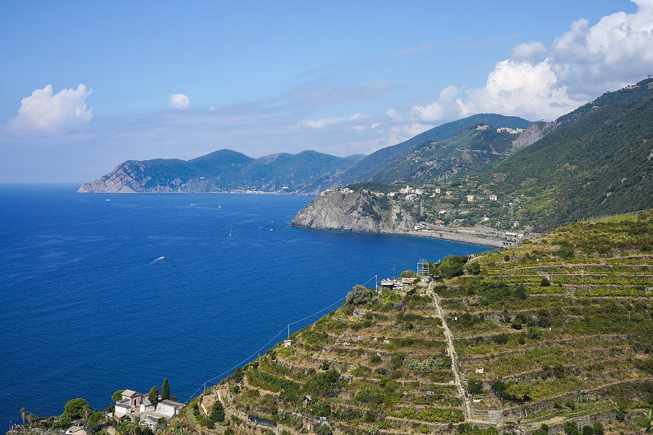 View of coastline NW from above Manarola: Manarola cemetery and fields and steep trail to Volastra in foreground, Cornig